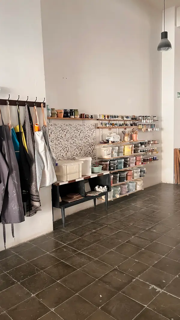 Delantales colgados junto a la estantería de herramientas y esmaltes del taller