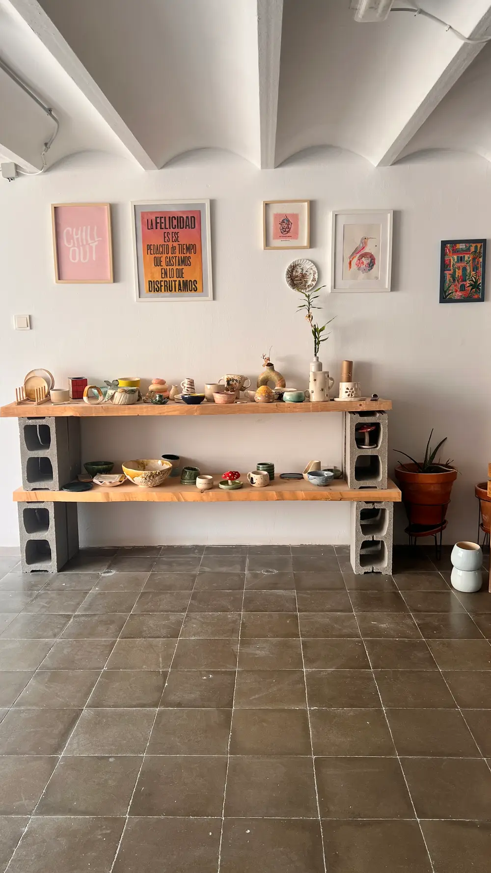 Mesa larga con cuencos, tazas y jarrones de cerámica terminados por las alumnas