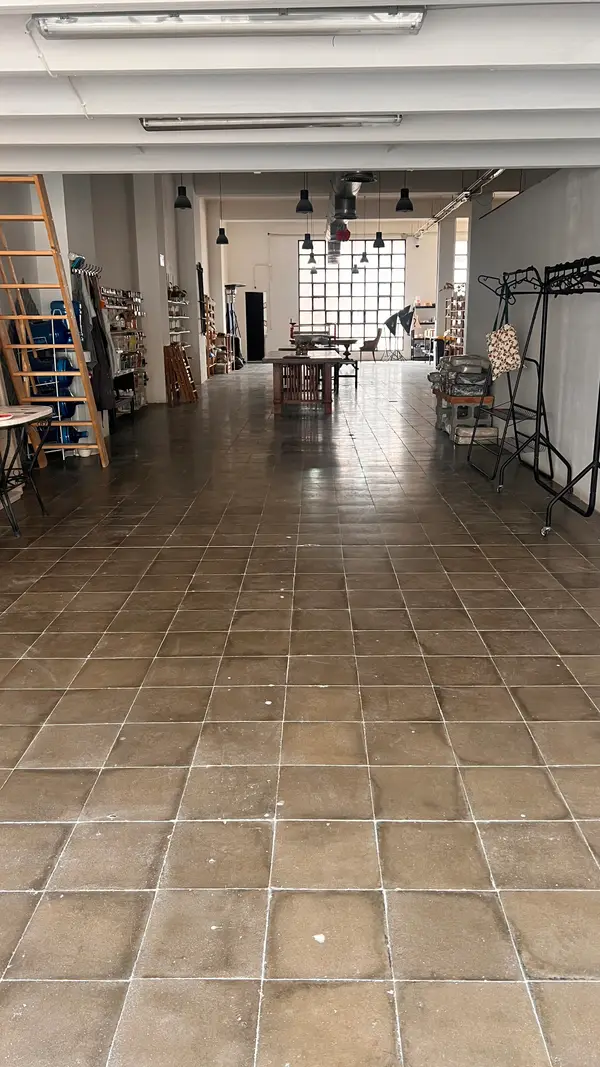 Vista del taller de cerámica a lo largo, con el ventanal del fondo y las estanterías de piezas